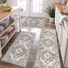 three rugs in the middle of a kitchen with wooden floors and white cabinets,