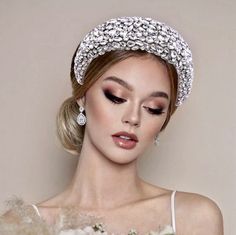 a woman in a white dress holding a bouquet and wearing a tiara with flowers on it