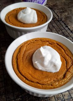 two white bowls filled with pumpkin pudding and whipped cream