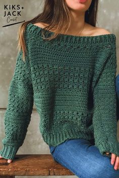 a woman sitting on top of a wooden bench wearing a green sweater