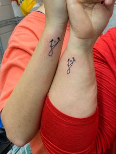 two people with matching tattoos on their arms, one is holding her hand up to the other