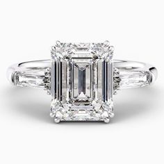 an emerald cut diamond ring with three baguets on the shoulders and side stones