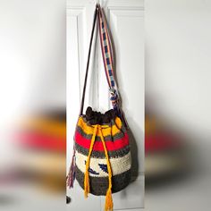 a multicolored purse hanging on a white door with yellow tasselled handles