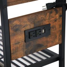 an electrical outlet is plugged into the side of a wooden table with metal slats