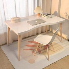 a laptop computer sitting on top of a white desk next to a chair and lamp