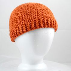 a white mannequin head wearing an orange knitted hat