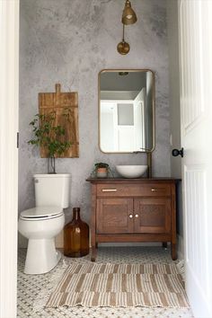 a bathroom with a sink, toilet and mirror in it's doorway way to another room