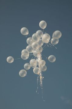 white balloons are floating in the air on a clear day