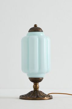 a light blue glass lamp on a metal base with a cord plugged in to it