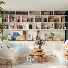 a living room filled with white furniture and lots of bookshelves on the wall