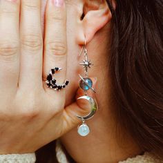 Stunning and sparkly celestial dangly earrings for boho women. These sterling silver earrings feature labradorite and Moonstone gemstones with celestial imagery including a star, planet Saturn and a crescent moon. Labradorite is commonly known as the stone of things ‘unseen.’ It provides energetic and spiritual protection while also warding off negative vibes. Moonstone delicately connects us to the wisdom of the moon and our own inner goddess. It is also deeply connected to water. Material: Gen Silver Spiritual Moon Phase Earrings, Celestial Silver Labradorite Jewelry, Handmade Silver Cosmic Jewelry, Celestial Silver Moonstone Earrings, Celestial Gemstone Drop Earrings, Silver Moon Phase Earrings, Mystical Moon Phase Dangle Earrings, Celestial Moon Phase Earrings, Silver Labradorite Jewelry With Moon Charm