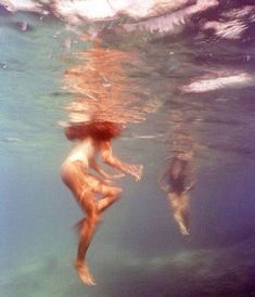 two people are swimming in the water with their backs turned to the camera and one person is diving