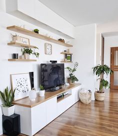 a living room filled with furniture and a flat screen tv on top of a wooden shelf