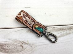 a pair of scissors is sitting on top of a leather keychain that has an arrow and leaf design on it