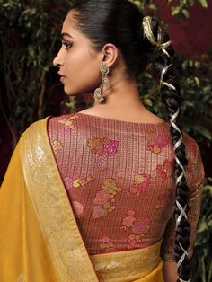 a woman with braids in her hair wearing a yellow sari and gold blouse