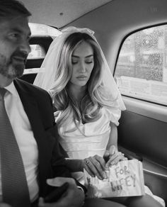 a bride and groom sitting in the back of a car