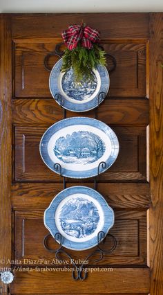 three blue and white plates are hanging on a wooden wall with a potted plant