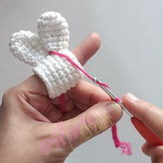 someone is crocheting an angel ornament with pink yarn and scissors in their hand