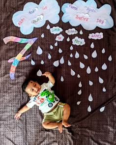 a baby laying on top of a bed covered in raindrops and paper cutouts