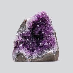 a rock with purple crystals sitting on it's side in front of a gray background