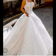 a woman in a white wedding dress standing on the street