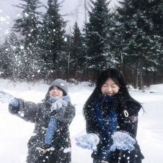 two women are playing in the snow with their hands up and one is pointing at something