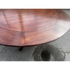 a large wooden table sitting on top of a cement floor next to a parking lot