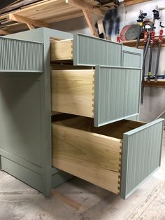 an unfinished cabinet with drawers in a garage