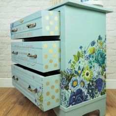 three drawers are painted with flowers and polka dots on the bottom one drawer is blue