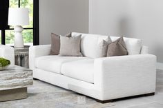 a living room with white couches and pillows on the floor next to a coffee table