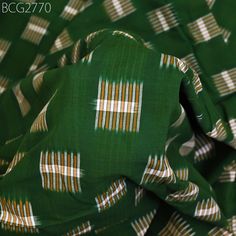 a green and white fabric with gold stripes on the top is folded up to show it's pattern