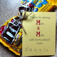 a candy bar wrapped in yellow paper with a note attached to it that says, thanks for driving m & m and miles with me to school love