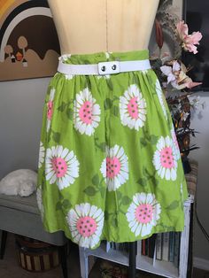 "Cute as can be! Apple green with whimsical flowers in white and neon pink. Attached white cotton and lace petticoat. Two tiny Frey's in fabric at the hem pictured. Easily repaired. Measurements: 26\" waist 42\" free flared hips 70\" circumference at hem 1-3/4\" waistband 7-1/2\" back nylon zipper with two button waist closure 19\" from top of the waistband to hem from the back" Spring Cotton Skirt For Garden Party, Spring Green Cotton Skirt, Green Cotton Skirt For Spring, Spring Garden Party Cotton Skirt, Fitted Spring Petticoat, Spring Mini Skirt Petticoat With Lined Skirt, Spring Mini Skirt Petticoat With Lining, Spring Fitted Lined Petticoat, Green Cotton Bottoms With Gathered Skirt