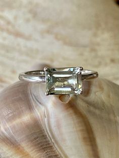 This classic East West solitaire setting contains a beautiful 2.00ct genuine prasiolite. The emerald cut stone measures approximately 8x6mm. The ring is available in sterling silver, and 14k white, yellow, or rose gold. This ring makes a great promise or engagement ring. Please send me a message if you need a size not listed. * This ring can be customized with any color center stone. All items are handmade by me in my shop in Woodbridge, NJ. Please message me with any questions. Shipping within Princess Cut Solitaire Topaz Ring For Formal Occasions, Sterling Silver Emerald Ring With Baguette Cut Center Stone, Classic Radiant Cut Topaz Ring Gift, Classic White Gold Baguette Cut Topaz Ring, Baguette Cut Emerald Ring With Center Stone, Elegant Solitaire Princess Cut Topaz Ring, Formal Emerald Cut Solitaire Topaz Ring, Formal Emerald-cut Solitaire Topaz Ring, Elegant Princess Cut Solitaire Topaz Ring