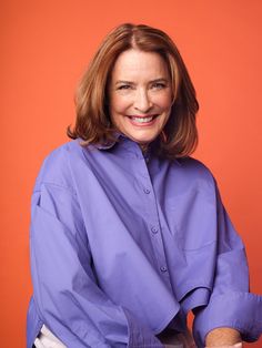 a woman in a purple shirt is posing for the camera with her hands on her hips