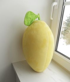 a yellow stuffed fruit sitting on top of a window sill