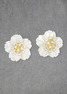 two white flowers with gold centers on a gray background, one is larger than the other