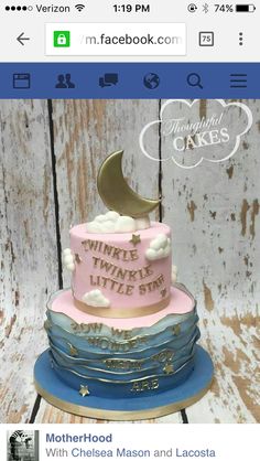 a three tiered cake with a moon and stars on top, sitting on a wooden table