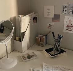 a white desk topped with lots of papers and other office supplies next to a mirror