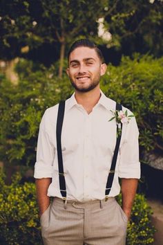 a man with suspenders and a flower in his lapel is smiling at the camera