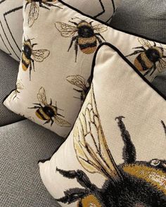 three pillows with bees on them sitting on a couch