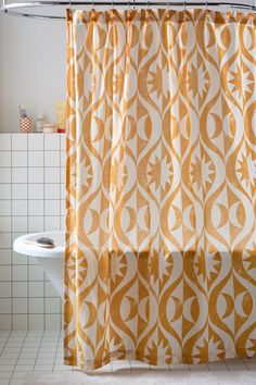 an orange and white shower curtain hanging from a metal rod in front of a bathtub