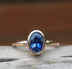 This stunning cornflower blue oval sapphire makes an unusual take on the classic sapphire engagement ring. Sapphires come in a rainbow of colours, all of them very beautiful. This particular sapphire ring has sold but if you would like something similar I can get stones in for you to see. The sapphire is 8x 6mm and was a very deep stone coming in at 1.98ct. It is set in recycled 9ct rose gold with a 2.5mm comfort fit band. Just ask for a quote if you would like a similar style ring with other co Contemporary Sapphire Ring, Bezel Sapphire Ring, Blue Sapphire Oval Cabochon Ring For Wedding, Blue Sapphire Oval Cabochon Wedding Ring, Blue Sapphire Ring With Oval Cabochon For Wedding, Coloured Stone Engagement Rings, Sapphire Engagement Ring Gold, Colored Stone Engagement Rings, Oval Sapphire Engagement Ring