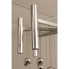 several silver balls hanging from a metal rack in a room with white walls and ceiling