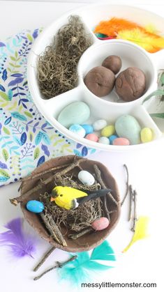 a bowl filled with chocolate eggs and birds nest on top of a table next to some feathers