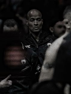 a black and white photo of a man standing in front of a crowd with his hand on his hip