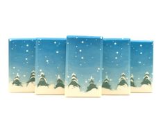 four pieces of blue and white glass with snow covered trees in the sky on them