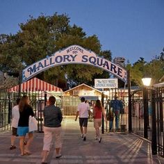 people walking under an entrance to mallory square