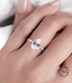 a woman's hand with a white diamond ring on her finger and the top half of her engagement ring