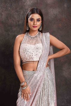 Get set to dazzle at cocktail parties in this beautiful silver sequin georgette pre-draped saree. The saree comes with a stunning designer halter-neck saree blouse.